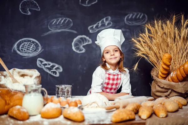 Bedårande liten flicka i kockmössa att göra degen — Stockfoto