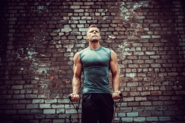 Spor salonunda spor yapan sporcu, esneme bandıyla egzersiz yapıyor..