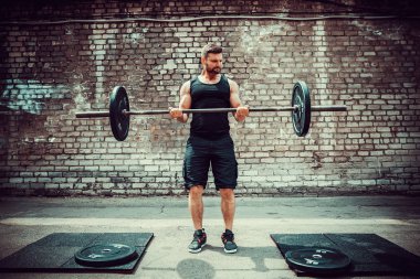 Atletik bir adam bir halter ile çalışma dışarı. Güç ve motivasyon. Pazı egzersiz.