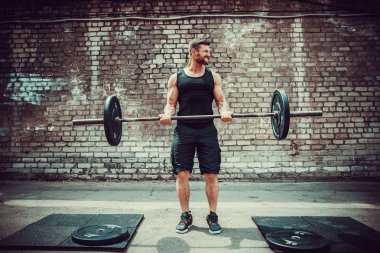 Atletik bir adam bir halter ile çalışma dışarı. Güç ve motivasyon. Pazı egzersiz.