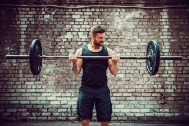 Atletik bir adam bir halter ile çalışma dışarı. Güç ve motivasyon. Pazı egzersiz.