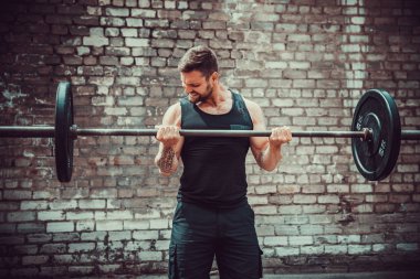 Atletik bir adam bir halter ile çalışma dışarı. Güç ve motivasyon. Pazı egzersiz.