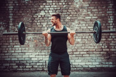 Atletik bir adam bir halter ile çalışma dışarı. Güç ve motivasyon. Pazı egzersiz.