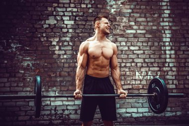 Atletik bir adam bir halter ile çalışma dışarı. Güç ve motivasyon. Pazı egzersiz.