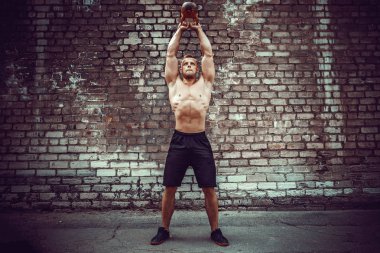 Atletik bir adam bir kettlebell ile çalışma dışarı. Güç ve motivasyon