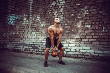 Atletik bir adam bir kettlebell ile çalışma dışarı. Güç ve motivasyon