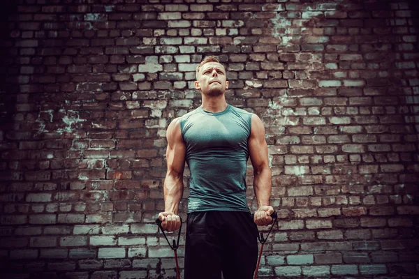 Spor salonunda spor yapan sporcu, esneme bandıyla egzersiz yapıyor..