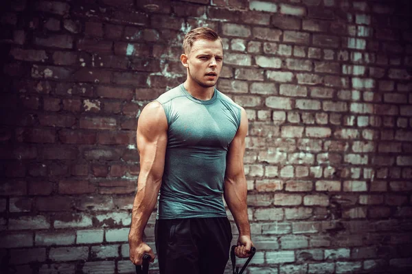 Hombre de fitness haciendo ejercicio con banda de estiramiento en gimnasio al aire libre . — Foto de Stock