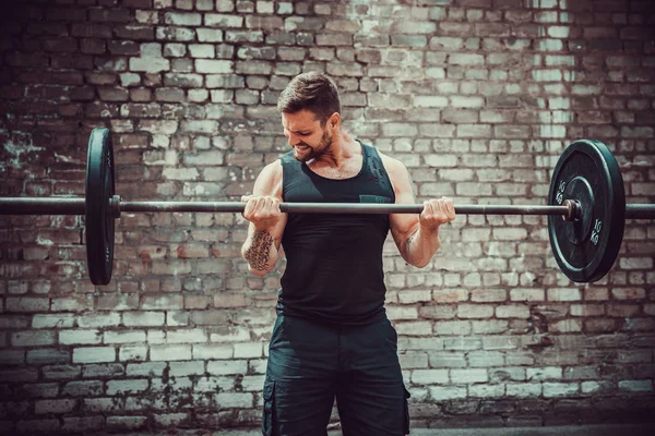 Athletischer Mann, der mit einer Langhantel trainiert. Stärke und Motivation. Bizeps-Übung. — Stockfoto