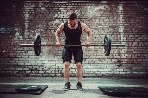 Homem atlético a treinar com um sino. Força e motivação. Exercício para os músculos das costas — Fotografia de Stock