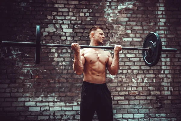 Hombre atlético haciendo ejercicio con una barra. Fuerza y motivación. Ejercicio bíceps . — Foto de Stock