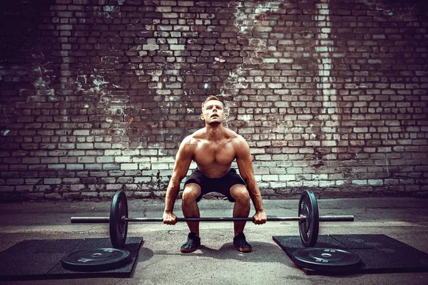 Gespierde fitness man doen deadlift een barbell boven zijn hoofd in outdoor, straat sportschool. Functionele training. — Stockfoto