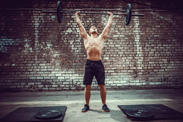 Svalová fitness člověk dělá deadlift činka nad hlavou v přírodě, pouliční tělocvičně. Funkční trénink. — Stock fotografie