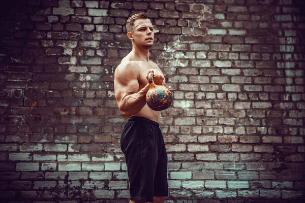 Hombre atlético haciendo ejercicio con un kettlebell. Fuerza y motivación — Foto de Stock