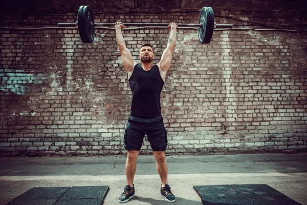 Homem de fitness muscular fazendo deadlift um sino sobre a cabeça no exterior, ginásio de rua. Treinamento funcional . — Fotografia de Stock