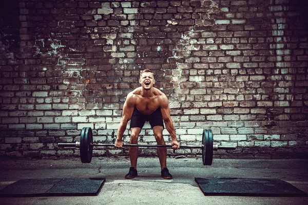 Svalová fitness člověk dělá deadlift činka nad hlavou v přírodě, pouliční tělocvičně. Funkční trénink. — Stock fotografie