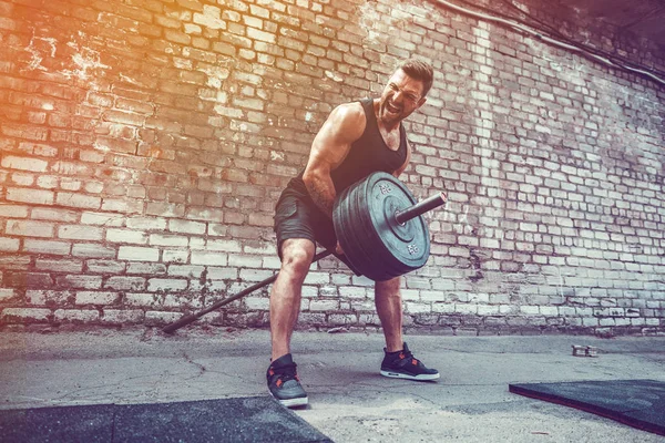 Hombre atlético haciendo ejercicio con una barra. Fuerza y motivación. Ejercicio para los músculos de la espalda — Foto de Stock