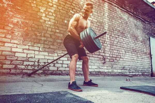 Homem atlético a treinar com um sino. Força e motivação. Exercício para os músculos das costas — Fotografia de Stock