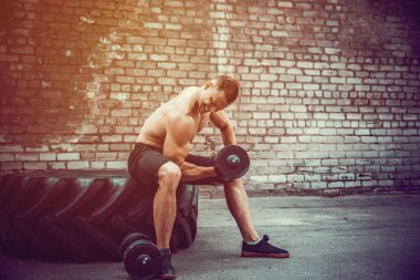 kaslı adam bir tuğla duvara dumbbell ile yapıyor