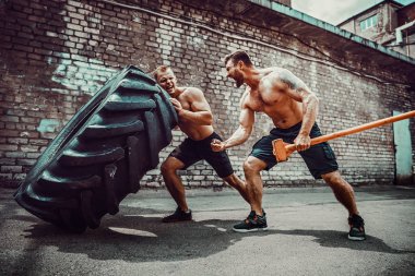 İki kaslı sporcu eğitim. Kas fitness gömleksiz adam büyük lastik taşıma