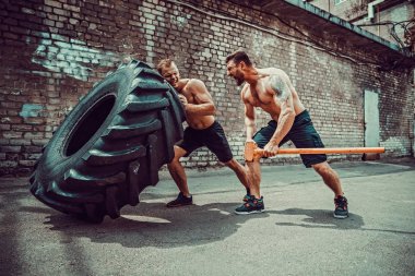 İki kaslı sporcu eğitim. Kas fitness gömleksiz adam büyük lastik taşıma