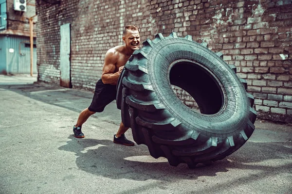 Svalová fitness shirtless muž pohybující se velké pneumatiky. — Stock fotografie