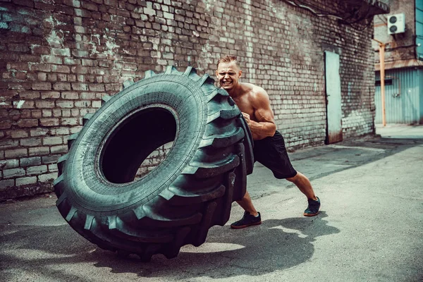 Svalová fitness shirtless muž pohybující se velké pneumatiky. — Stock fotografie