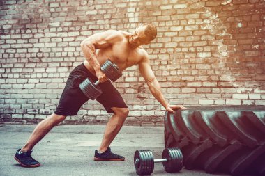 Atletik bir adam bir halter ile çalışma dışarı. Güç ve motivasyon. Arka kasları için egzersiz