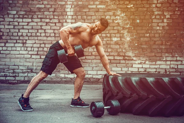 Homem atlético a treinar com um halteres. Força e motivação. Exercício para os músculos das costas — Fotografia de Stock