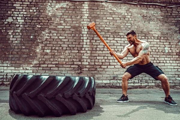Sport Fitness Man raken wiel band met hamer Sledge Cross fit Training. — Stockfoto