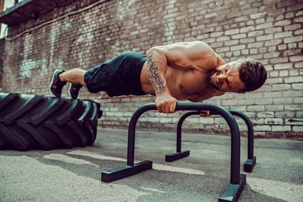 Tahta açık havada tutarak basın egzersizleri yapıyor güçlü sportif mutlu neşeli pozitif adam — Stok fotoğraf