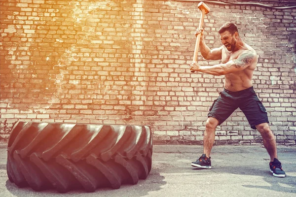 Sport Fitness Man Hitting Wheel Tire With Hammer Sledge Crossfit Training.