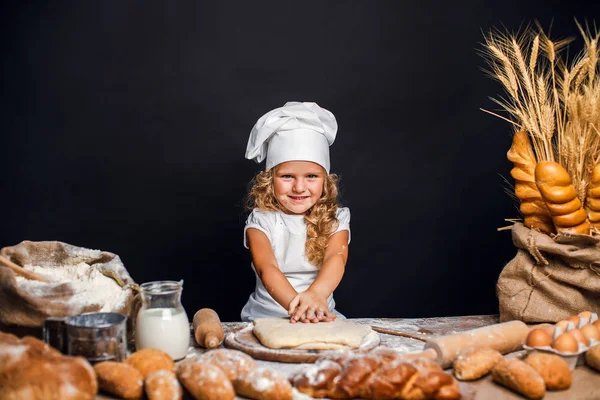 Menina amassando massa de farinha à mesa — Fotografia de Stock