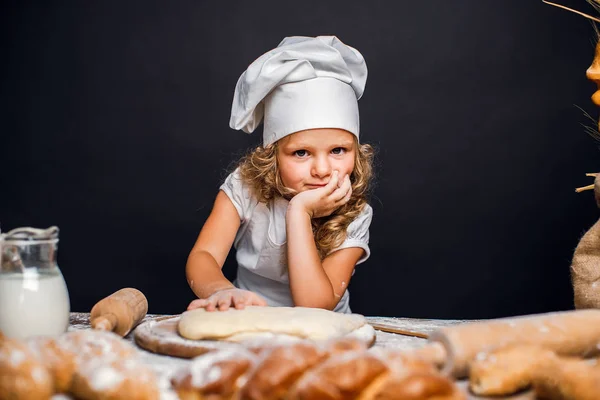 Menina amassando massa de farinha à mesa — Fotografia de Stock