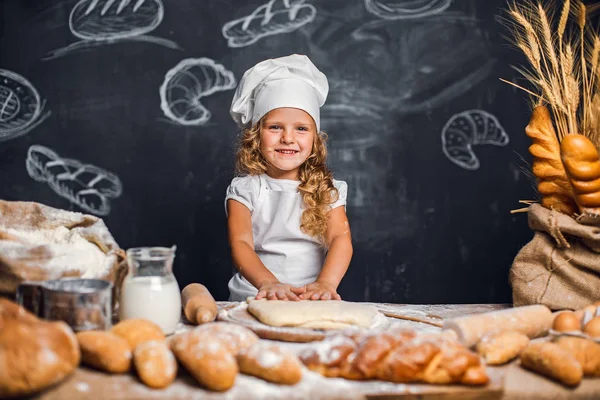 Menina amassando massa de farinha à mesa — Fotografia de Stock