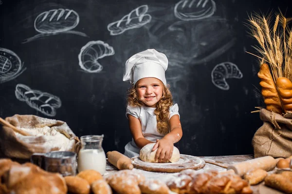 Menina amassando massa de farinha à mesa — Fotografia de Stock