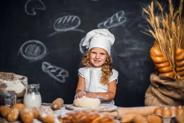 Маленька дівчинка замінює тісто за столом — стокове фото