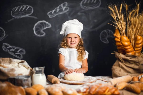 Menina amassando massa de farinha à mesa — Fotografia de Stock