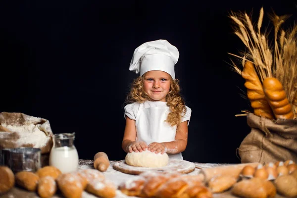 Menina amassando massa de farinha à mesa — Fotografia de Stock