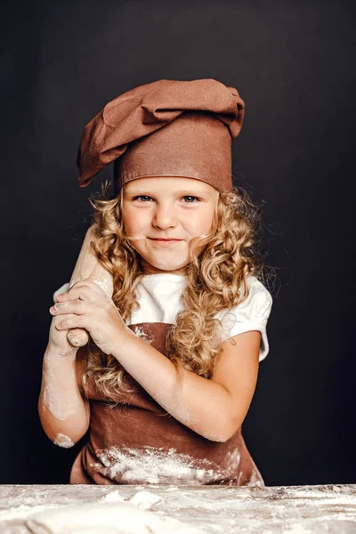 Menina amassando massa de farinha à mesa — Fotografia de Stock