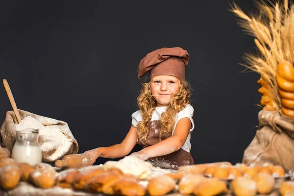 Menina amassando massa de farinha à mesa — Fotografia de Stock