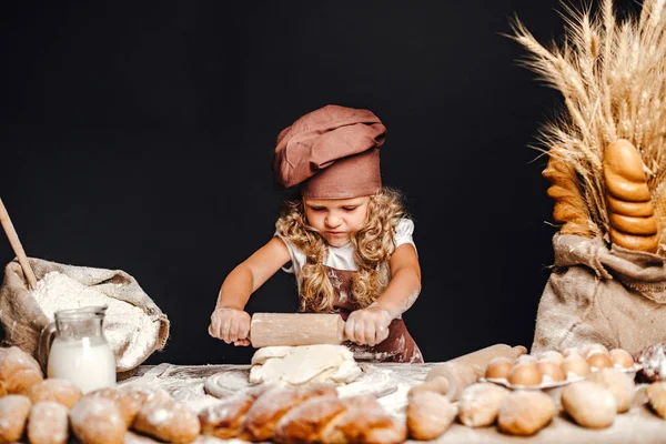 Menina amassando massa de farinha à mesa — Fotografia de Stock