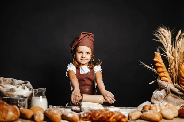 Menina amassando massa de farinha à mesa — Fotografia de Stock