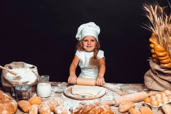 Маленька дівчинка замінює тісто за столом — стокове фото