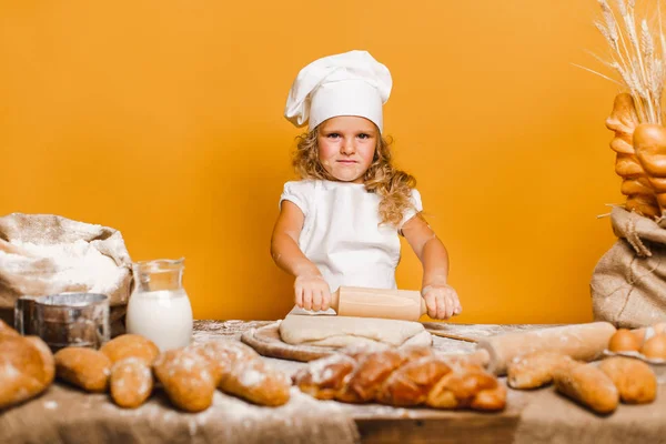 Menina amassando massa de farinha à mesa — Fotografia de Stock