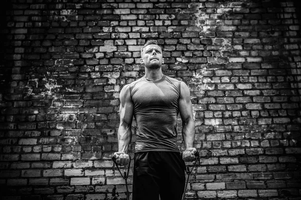 Hombre de fitness haciendo ejercicio con banda de estiramiento en gimnasio al aire libre . — Foto de Stock