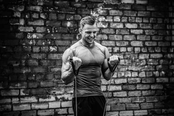 Fitness man exercising with stretching band in outdoor gym.