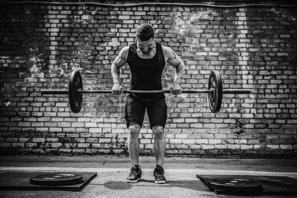 Gespierde fitness man doen deadlift een barbell boven zijn hoofd in outdoor, straat sportschool. Functionele training. — Stockfoto