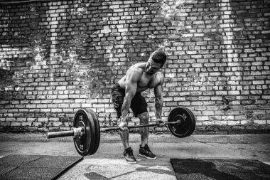 Atletik bir adam bir halter ile çalışma dışarı. Güç ve motivasyon. Arka kasları için egzersiz