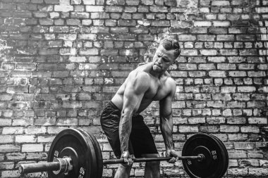 Atletik bir adam bir halter ile çalışma dışarı. Güç ve motivasyon. Arka kasları için egzersiz